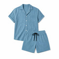 Mann trägt blaues Cord-Set mit Camp Collar und Tunnelzug-Shorts in entspannter Pose