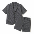 Mann trägt schwarzes Karo-Set aus Kurzarm-Blazer und Shorts, Slim Fit, aufrechte Pose, Ganzkörperaufnahme