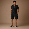 Geripptes Herren-Set in Schwarz — Poloshirt mit Viertelreißverschluss und passende Shorts, Frontansicht auf neutralem Hintergrund